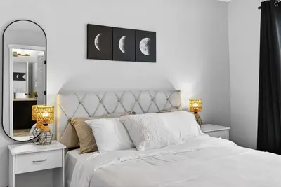 a bedroom with a white bed with two lamps and a mirror at modern 3bedroom space sleeps 6 free parking in Edmonton