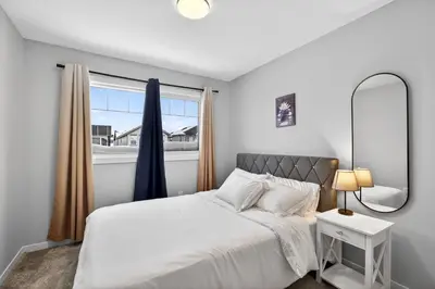 a bedroom with a bed with a mirror and a window at modern 3bedroom space sleeps 6 free parking in Edmonton