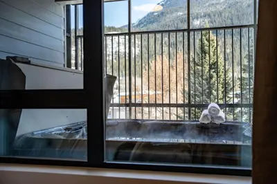 a view from a window of a tub with a mountain view at The Peaks and Birdies in Mackenzie Village, Revelstoke in Revelstoke
