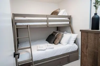 a bunk bed with white sheets and pillows on it at The Peaks and Birdies in Mackenzie Village, Revelstoke in Revelstoke