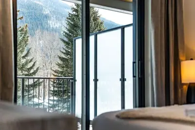 a bedroom with a large window with a mountain view at The Peaks and Birdies in Mackenzie Village, Revelstoke in Revelstoke