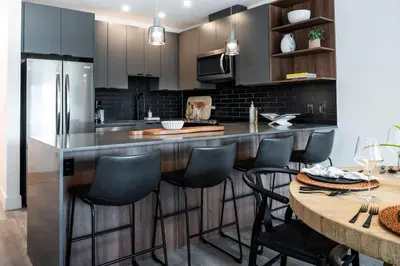 a kitchen with a large island with blue bar stools at Alpine Ascent with Hot Tub in Mackenzie Village in Revelstoke
