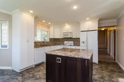 a kitchen with white cabinets and a marble counter top at Quiet Furnished Room Near Transit and Hospital long stays in Surrey