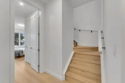 an open hallway with white walls and wooden floors at Shaganappi 2BR with private Baths, Walk to CTrain, Garage Parking, Full Kitchen in Calgary