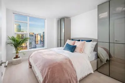 a bedroom with a bed and a large window at Downtown 2-Bedroom Apartment with Beautiful City Views in Vancouver
