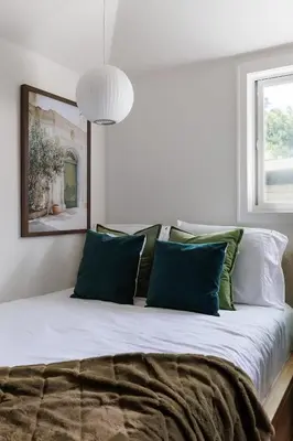 a bedroom with a bed with green and white pillows at The Garden Studio in Victoria