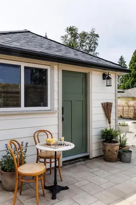 a patio with a table and chairs and a green door at The Garden Studio in Victoria