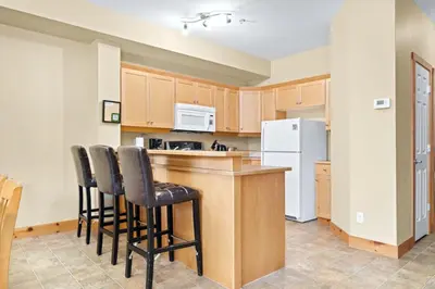 a kitchen with wooden cabinets and a white refrigerator at 2BR Kimberley Escape with Private Hot Tub and BBQ in Kimberley