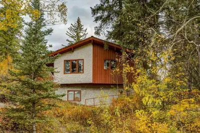 a house on top of a hill with trees at Eagles Nest Chalet with Private Deck Near Banff in Canmore