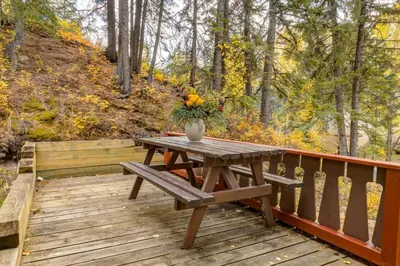 a wooden deck with a picnic table with flowers on it at Eagles Nest Chalet with Private Deck Near Banff in Canmore