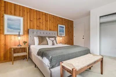 a bedroom with a large bed and a wooden wall at 2BR Red Cedar Lodge near Banff with Mountain Views in Canmore