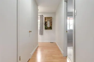 a hallway with white walls and a wooden floor at 2BR Red Cedar Lodge near Banff with Mountain Views in Canmore