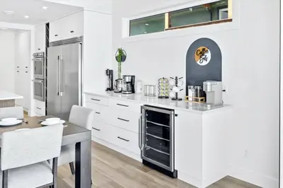 a kitchen with white cabinets and a table with a dining room at Luxurious 4BR Beach Retreat with Backyard and Balcony in Penticton