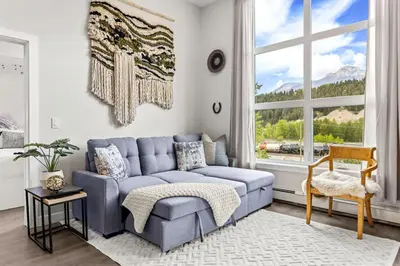 a living room with a blue couch and a window at Luxe 3BR Golden Hideaway Top Floor, Balcony & BBQ in Golden