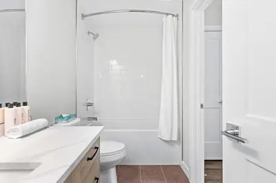 a white bathroom with a toilet and a shower at Scenic Riverstone 2BR w/ Balcony + BBQ, Sleeps 6! in Golden