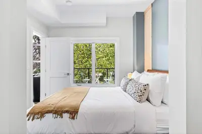a white bedroom with a large bed and a window at Scenic Riverstone 2BR w/ Balcony + BBQ, Sleeps 6! in Golden