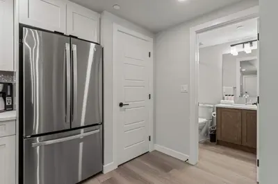 a kitchen with a stainless steel refrigerator and white cabinets at Brand New 3BR Rockies Haven w/ Balcony, Pool & Gym in Dead Man's Flats