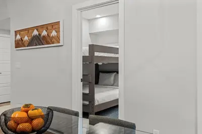 a room with a table and a bedroom with a bunk bed at Brand New 3BR Rockies Haven w/ Balcony, Pool & Gym in Dead Man's Flats
