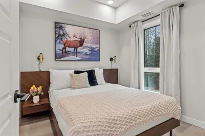 a bedroom with a bed with a deer painting on the wall at Brand New 3BR Rockies Haven w/ Balcony, Pool & Gym in Dead Man's Flats