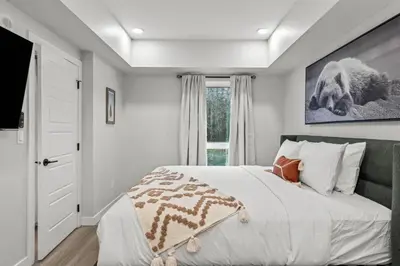 a white bedroom with a bed and a window at Brand New 3BR Rockies Haven w/ Balcony, Pool & Gym in Dead Man's Flats