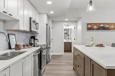 a kitchen with white cabinets and a counter top at Brand New 3BR Rockies Haven w/ Balcony, Pool & Gym in Dead Man's Flats