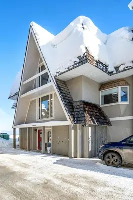 a snow covered house with a car parked in front at Kimberley Escape: 1BR+Studio w/ Hot Tub, Pool, BBQ in Kimberley