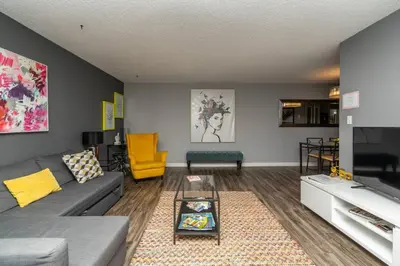 a living room with a gray couch and a yellow chair at Stylish DT Condo ~2 Blocks from Stampede Grounds in Calgary