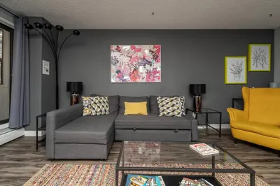 a living room with a gray couch and a yellow chair at Stylish DT Condo ~2 Blocks from Stampede Grounds in Calgary