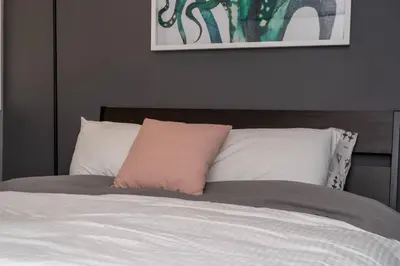 a bed with a pink pillow on top of it at Stylish DT Condo ~2 Blocks from Stampede Grounds in Calgary