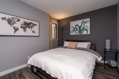 a bedroom with a large white bed and paintings on the wall at Stylish DT Condo ~2 Blocks from Stampede Grounds in Calgary