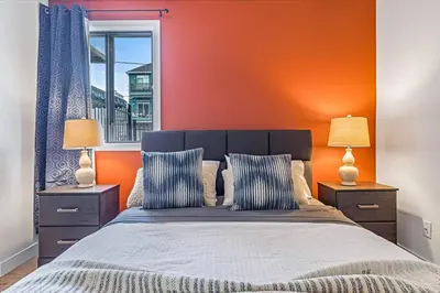 a bedroom with an orange wall and a bed with two lamps at Stampede Modern downtown Condo Spacious 2BR in Calgary