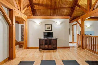 a large living room with wooden ceilings and a television and a table with mats at Highlands Homestead Luxury Retreat in Bragg Creek