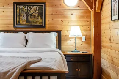 a bedroom with a bed and a lamp on a night stand at Highlands Homestead Luxury Retreat in Bragg Creek