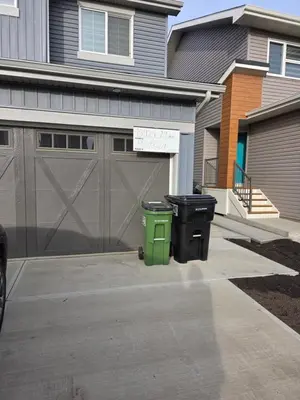 two trash cans sitting in front of a garage at Amaville Suites - One Bedroom in West Edmonton in Edmonton
