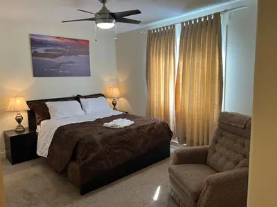 a bedroom with a bed and a chair and a ceiling fan at Modern Vacation Home Near West Edmonton Mall, Transit Center & LRT - 3BR in Edmonton