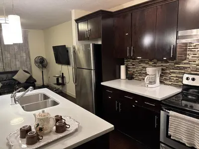 a kitchen with a sink and a refrigerator at Modern Vacation Home Near West Edmonton Mall, Transit Center & LRT - 3BR in Edmonton