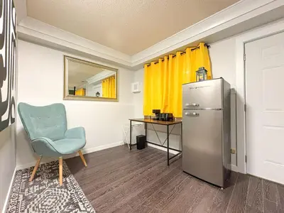 a room with a refrigerator and a chair and a table at Vancouver UBC 2BD Suite in Vancouver