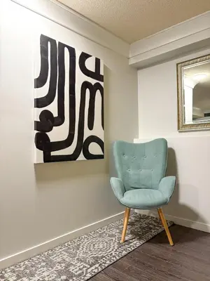 a blue chair in a room with a painting at Vancouver UBC 2BD Suite in Vancouver