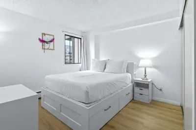 a white bedroom with a bed and a desk at Bright 2 Bedroom Suite at Victoria & Stampede Park in Calgary