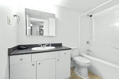 a white bathroom with a sink and a toilet at Bright 2 Bedroom Suite at Victoria & Stampede Park in Calgary
