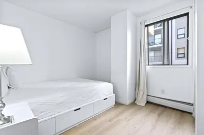 a white bedroom with a bed and a window at Bright 2 Bedroom Suite at Victoria & Stampede Park in Calgary