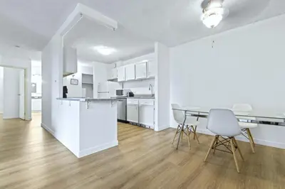 a white kitchen and dining room with a table and chairs at Bright 2 Bedroom Suite at Victoria & Stampede Park in Calgary