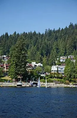 a small sail boat in the water near a harbor at Cozy Deep Cove Retreat Near Quarry Rock Hike in North Vancouver