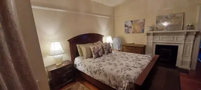 a bedroom with a bed and two lamps and a fireplace at Rosewood in New Westminster