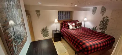 a bedroom with a bed with a red plaid blanket at Rosewood Garden Studio in New Westminster