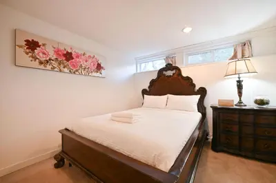 a bedroom with a bed and a dresser and a window at Basement Suite in South Vancouver in Vancouver