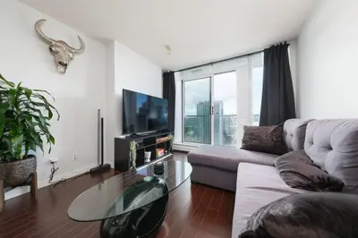 a living room with a couch and a large window at Cozy Condo in Prime Location with Jacuzzi Pool & Sauna in Vancouver