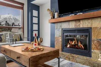 a living room with a fireplace and a table with food at Heart of Canmore Condo managed by Little Sister Getaways in Canmore
