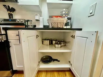 a kitchen with white cabinets and pots and pans at AK Stay in Abbotsford