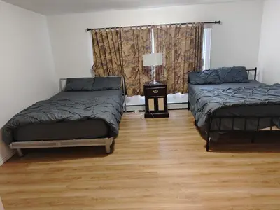 a room with two beds and a lamp on a wooden floor at Vancouver Private Rooms - Free Parking, Fast Wi-Fi, Easy Transit - 15 mins Downtown & 11 mins Airport in Vancouver
